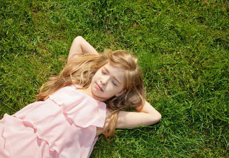 little girl lying on green grassの写真素材