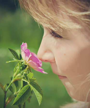 young girl smelling pink blossomの写真素材