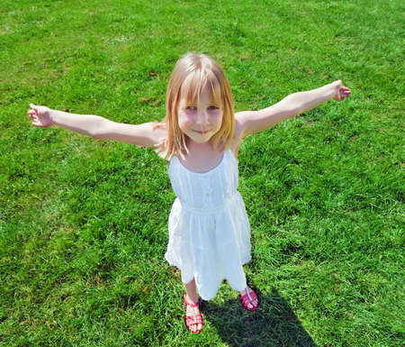 beautiful child with raised standing on green grass