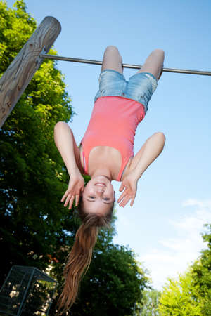 girl hanging upside down on horizontal bar