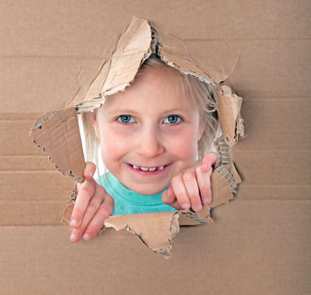 girl looking through hole in cardboardの写真素材