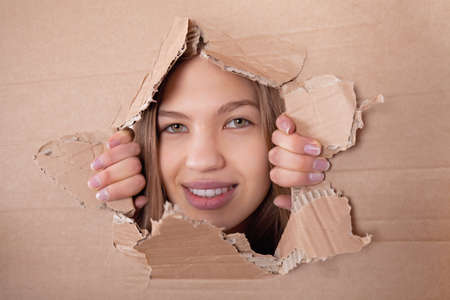 girl looking through hole in cardboardの写真素材