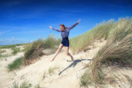 girl jumping from sand duneの写真素材