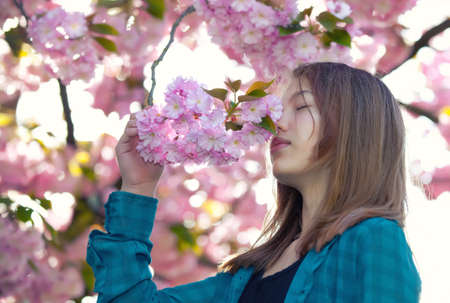 young girl smelling pink blossoms