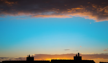 Colorful sky in the evening with chimneys and a layer of cloudsの写真素材