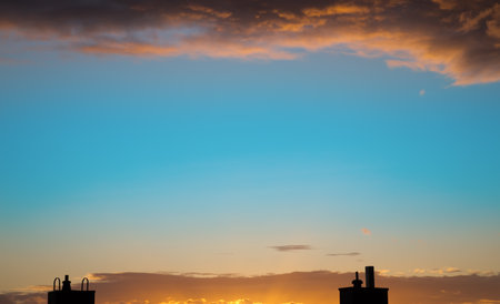 Colorful sky in the evening with chimneys and a layer of cloudsの写真素材