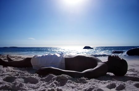 black man laying on the beachの写真素材