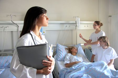 Portrait of a doctor with two of her co-workers talking with a patient in the background の写真素材