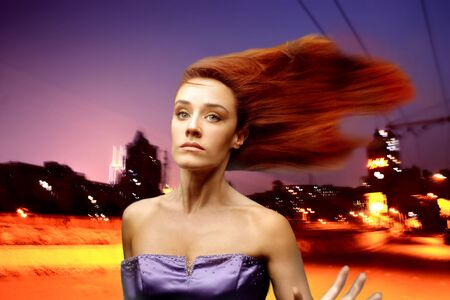 elegant woman with flying hair and a city at nightの写真素材