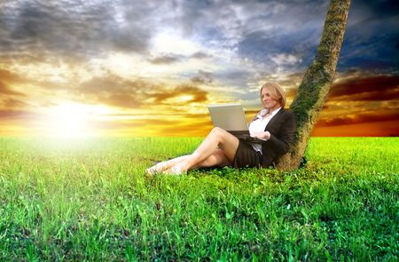 attractive business woman lying on grass field with laptopの写真素材
