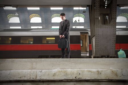 Businessman standing on the platform of a train stationの写真素材