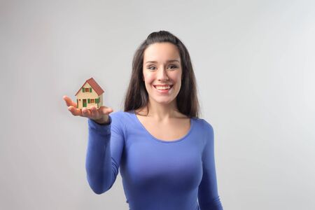 Smiling young woman holding the model of a house in her handの写真素材
