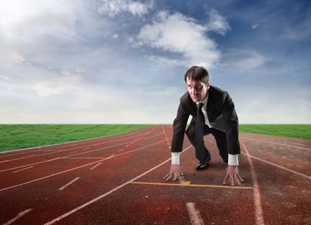 Businessman kneeling on the starting grid of a running trackの写真素材