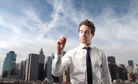 Businessman drawing an airplane with cityscape on the backgroundの写真素材