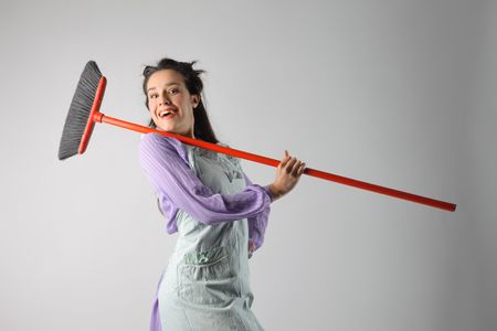 Smiling housewife carrying a broom on her shoulderの写真素材