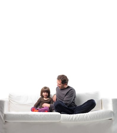 Father tickling his daughter on a sofaの写真素材