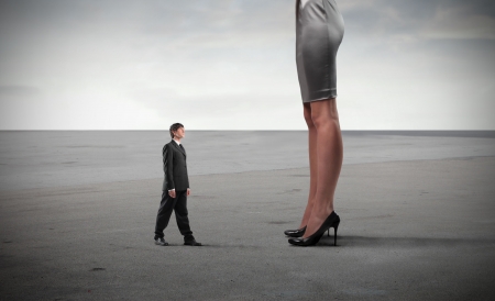 Tiny businessman standing in front of a giant woman's legsの写真素材
