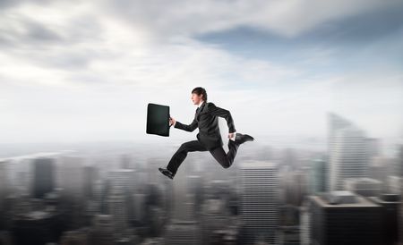 Businessman running fast over a cityの写真素材