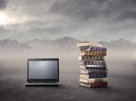 Laptop lying beside a stack of books