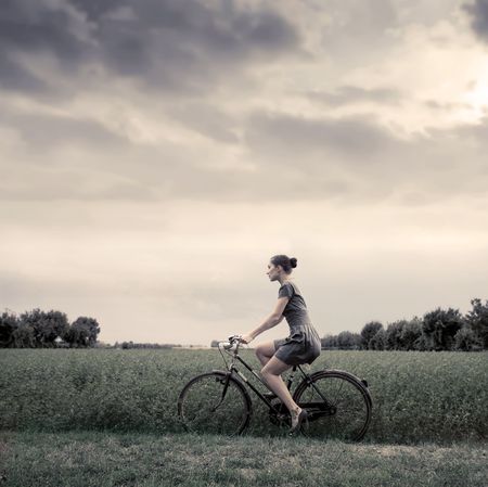 Vintage portrait of a woman riding a bike in the countryの写真素材