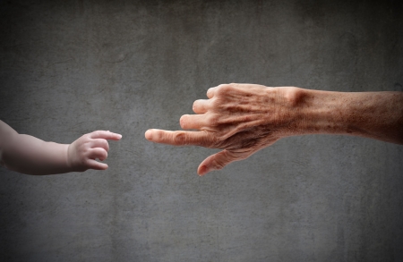 Senior's hand touching a child's handの写真素材