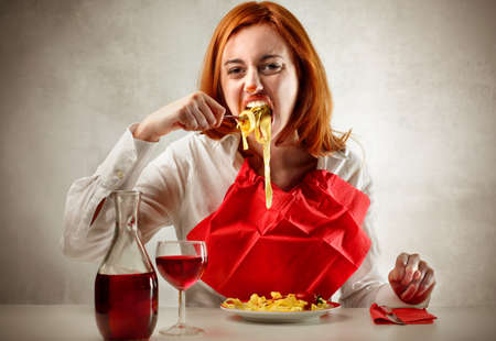 Young woman eating with pleasure a plate of tagliatelle の写真素材