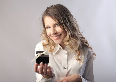Smiling beautiful woman holding a small giftの写真素材