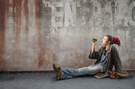 Young woman in alternative clothes drinking a beerの写真素材