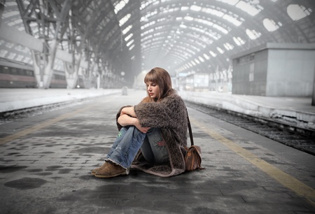 Young woman sitting on the platform of a train station