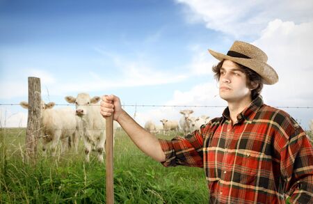 Young farmer on a green meadow with animals on the backgroundの写真素材