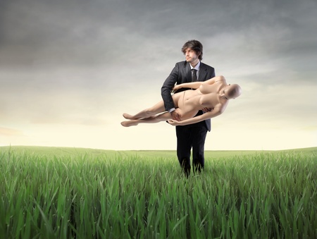 Businessman carrying a mannequin on a green meadowの写真素材