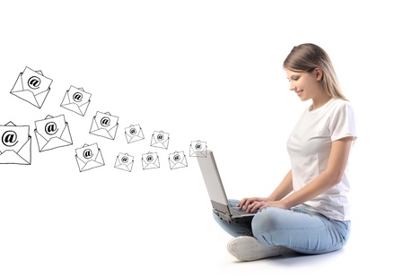 Smiling woman sending e-mails from a laptop