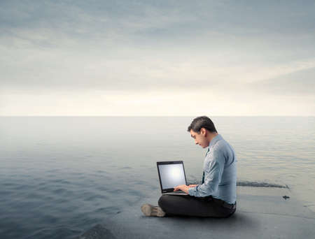 Businessman using a laptop on a wharfの写真素材