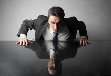 Astonished businessman lookng at his reflex on a table