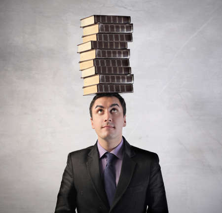 Man with stack of books on his headの写真素材