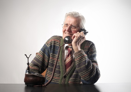 Smiling senior man talking to telephoneの写真素材