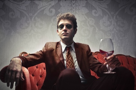 Elegant young man holding a glass of wineの写真素材