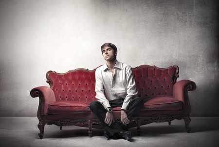 Handsome man sitting on a velvet sofaの写真素材