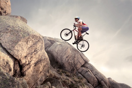 Cyclist climbing up a rock with his mountain bike Cyclist climbing up a rock with his mountain bike