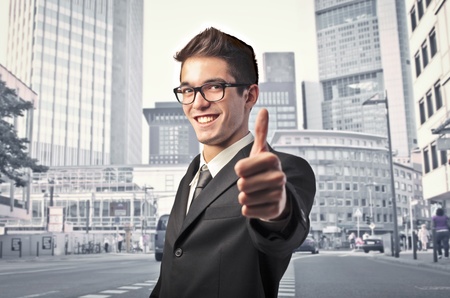 Smiling businessman with thumbs up and cityscape in the backgroundの写真素材
