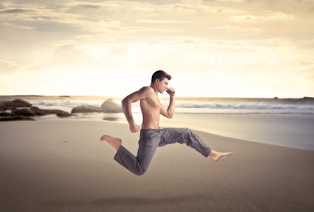 Handsome bare-chested man running on a beachの写真素材