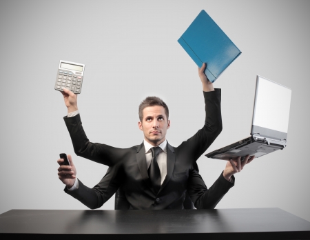 Businessman with four arms holding business toolsの写真素材