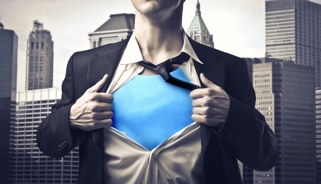 Closeup of a businessman showing the superhero suit under his shirt with cityscape in the backgroundの写真素材