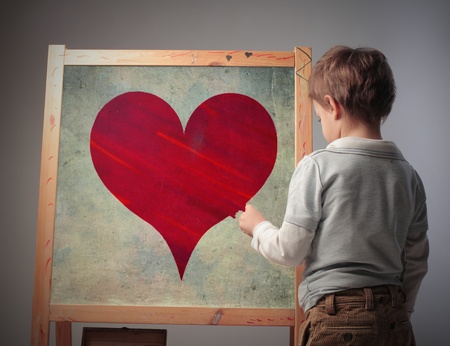 Child drawing a heart on a blackboardの写真素材