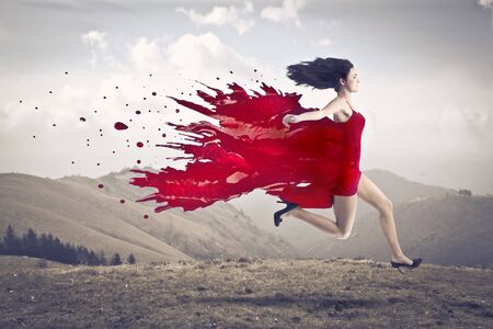 Beautiful woman running on a hill with her dress melting in red paint