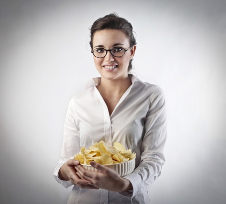 Young woman holding a bowl of chipsの写真素材