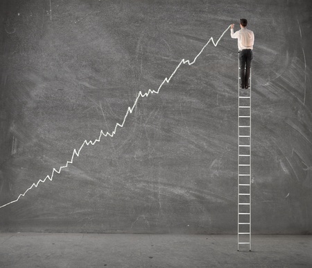 Young businessman on a ladder charting a positive trend graphの写真素材