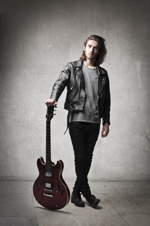Young man in leather jacket holding a guitarの写真素材