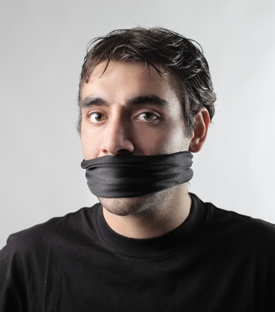Young man with his mouth closed by a bandageの写真素材