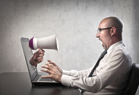 Businessman astonished by a megaphone poking out of his laptop screenの写真素材